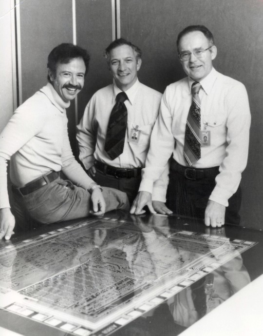 Эндрю Гроув, Роберт Нойс и Гордон Мур стоят над стеклянной конструкцией микропроцессора